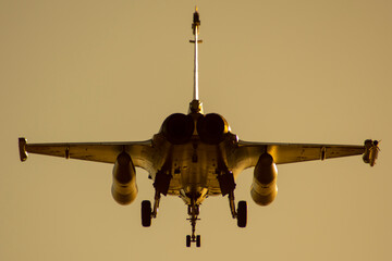 Avión de combate Rafale bimotor aterrizando al atardecer