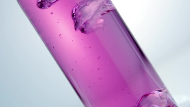 Pink liquid boils in a flask. Air bubbles. Elixir. Aromatherapy. Cosmetics. Flower serum. Minimalism in advertising. Beauty style. Getting the extract.  Condensate.