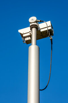 CCTV security camera system being used for surveillance with a clear blue sky, stock photo image with copy space