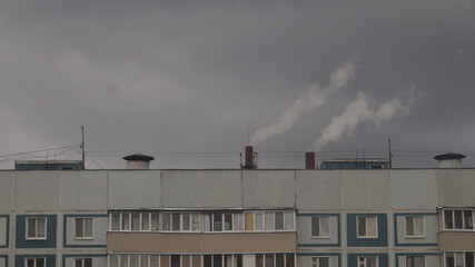 Smoke from pipes on the background of a multi-storey building