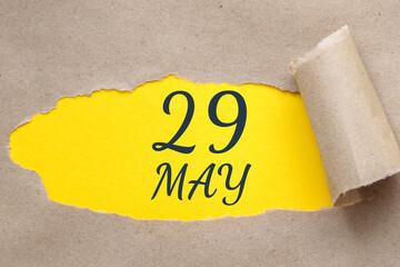 may 29. 29th day of the month, calendar date. Hole in paper with edges torn off. Yellow background is visible through ragged hole.Spring month, day of the year concept