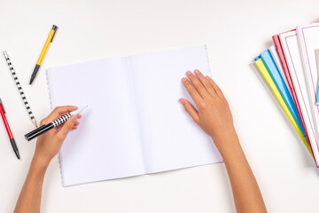 Kid hand holding pen in left hand and writing in open notebook, doing homework. Left Handers Day