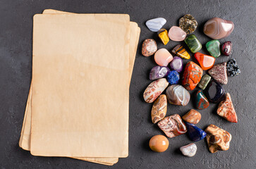 Mineral stones and an old piece of paper. Black concrete background. The concept of using minerals...