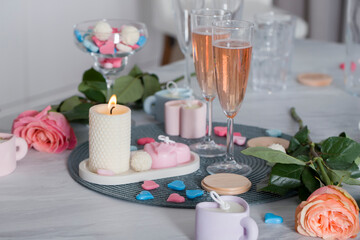 Obraz na płótnie Canvas Wax hearts on the table against the background of candles, flowers, champagne glasses.