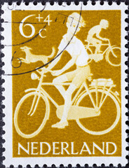 Netherlands - circa 1962: a postage stamp from the Netherlands , showing Children cycling with a dog