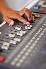 Fine-tuning the mix. Cropped close-up image of a hand moving a slider on a mixing desk.
