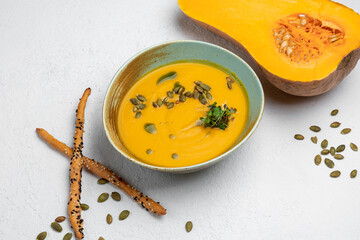 pumpkin soup garnished with pumpkin seeds on a white background