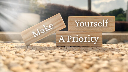 Make yourself a priority text on wooden blocks with bright sun and park background.