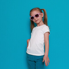 White t-shirt mockup, little european girl in summer clothes, sunglasses on a blue background