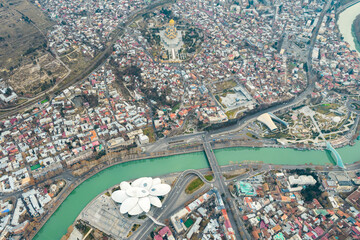 Fototapeta premium Aerial view of Tbilisi city center with churches and modern buildings and emerald waters of Kura river