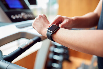 Close Up Of Woman In Gym Using Fitness App On Smart Watch On Running Machine