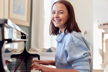 Portrait Of Smiling Teenage Girl At Home Playing The Piano
