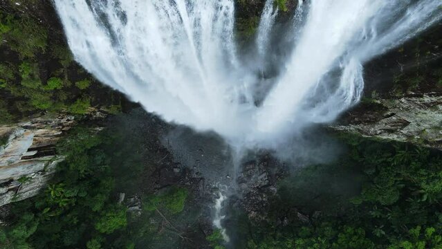 Rising slowly above a cascading waterfall as the water thunders down to a lush tropical rock pool below. Unique drone view