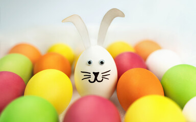 Funny bunny among colorful eggs. Holiday card. Easter background 