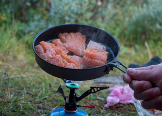 Close up of raw red trout fish fillet of freshly caught arctic char with green herbs, frying on...