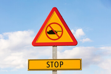 Danger traffic signal with a tank with a prohibited signal and a sign that says: 'STOP', with the sky in the background. Concept of War, Ukraine, Russia and war conflict.