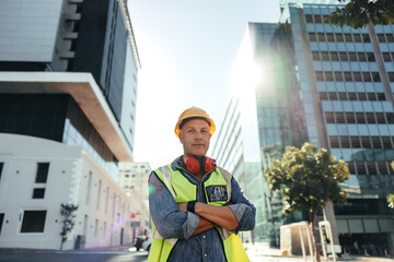 Self-confident construction worker standing with his arms crossed - obrazy, fototapety, plakaty