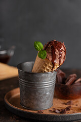Homemade chocolate ice cream cone with chocolate syrup and mint, vertical photo
