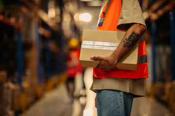 Worker carrying cardboard box at warehouse