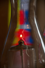 A glass, kerosene lamp burns as a memorial against a colorful background of stained glass inside a synagogue in Jerusalem. 