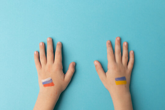 Children's hands with the flags of Russia and Ukraine as a symbol of goodness and peace. There is no war. Stop the war