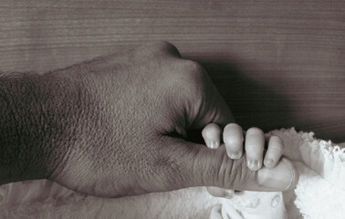 Newborn baby's finger clutching his father's hand