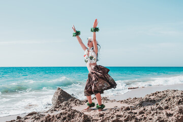 Hawaiian woman enjoys hula dancing on the beach barefoot wearing traditional costume