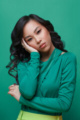 Beautiful asian girl in bright green clothes on a green background.