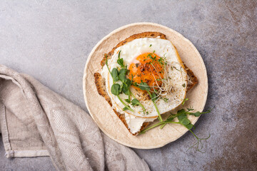 Tasty breakfast of fried egg on toast with microgreen