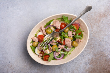 Healthy tuna salad with fresh arugula, cherry tomatoes, quail egg and olives