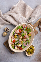 Healthy tuna salad with fresh arugula, cherry tomatoes, quail egg and olives