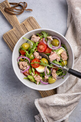 Healthy tuna salad with fresh arugula, cherry tomatoes, quail egg and olives