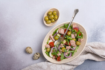 Healthy tuna salad with fresh arugula, cherry tomatoes, quail egg and olives