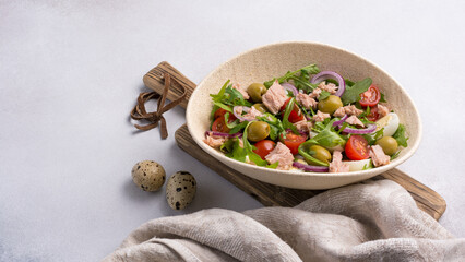 Healthy tuna salad with fresh arugula, cherry tomatoes, quail egg and olives