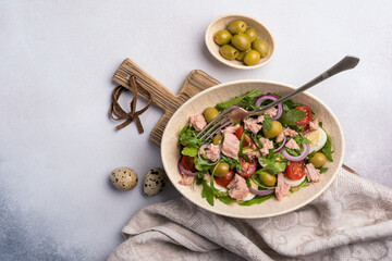 Healthy tuna salad with fresh arugula, cherry tomatoes, quail egg and olives