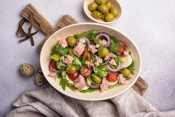 Healthy tuna salad with fresh arugula, cherry tomatoes, quail egg and olives