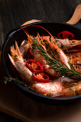 spicy langoustines with pepper and rosemary in a frying pan, served with a glass of wine