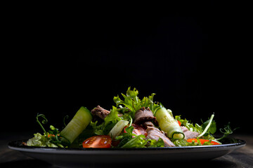 fresh vegetable salad and meat on dark wooden background