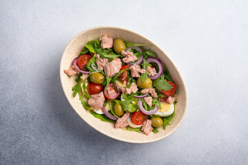 Healthy tuna salad with fresh arugula, cherry tomatoes, quail egg and olives