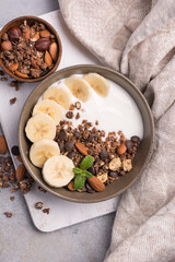 Healthy breakfast of granola with fresh banana, nuts, chocolate drops and yogurt