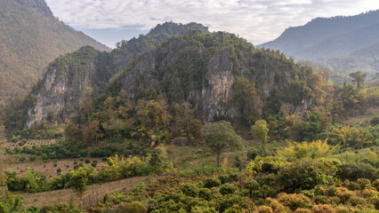 Beautiful landscape view of scenic limestone mountain with mango orchard in foreground in rural agricultural valley near Chiang Dao, Chiang Mai, Thailand