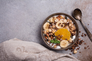 Healthy breakfast of granola with nuts, banana, orange and yogurt