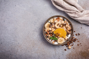 Healthy breakfast of granola with nuts, banana, orange and yogurt
