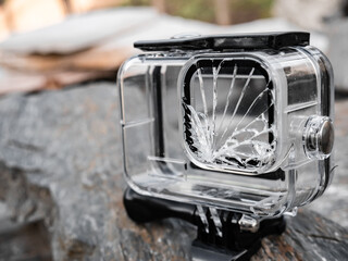 Transparent casing of a sports camera destroyed and unusable due to the impact on the ground of the lens part showing a good blow with the glass completely broken and deteriorated