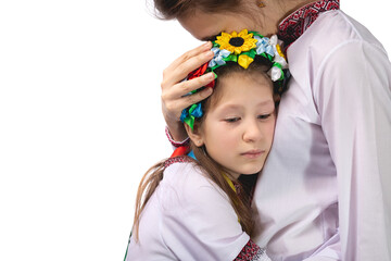 The mother hugs the child with tearful eyes. A child in Ukrainian national clothes.