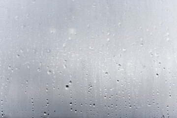 Steamy window with water drops made in dull day, condensation on glass with drops flowing down, humidity and foggy blank
