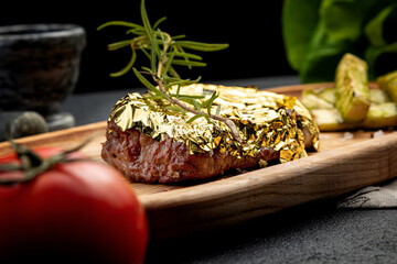 steak with gold garnished with a branch of rosemary served with french fries