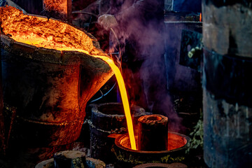 Molten metal flows out of the bucket. Soft focus