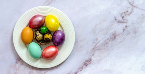 Beautiful Easter eggs painted in different beautiful colors on a plate on a marble surface. Celebration of Holy Easter.