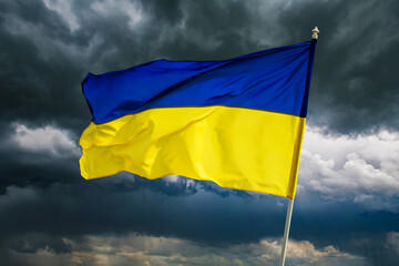 Ukrainian blue and yellow bicolor national flag on dark cloudy dramatic sky background. Ukraine fight for Freedom concept